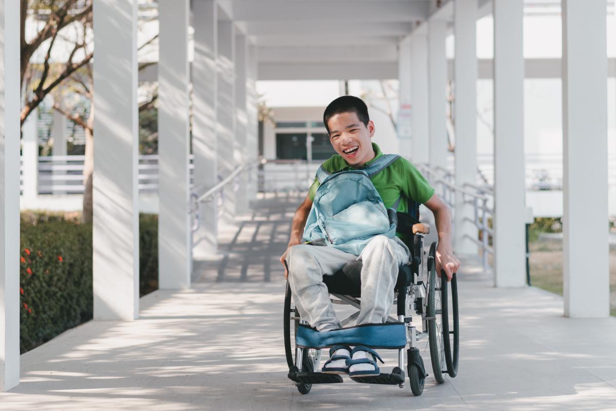 Young person in a wheelchair propelling down ramp