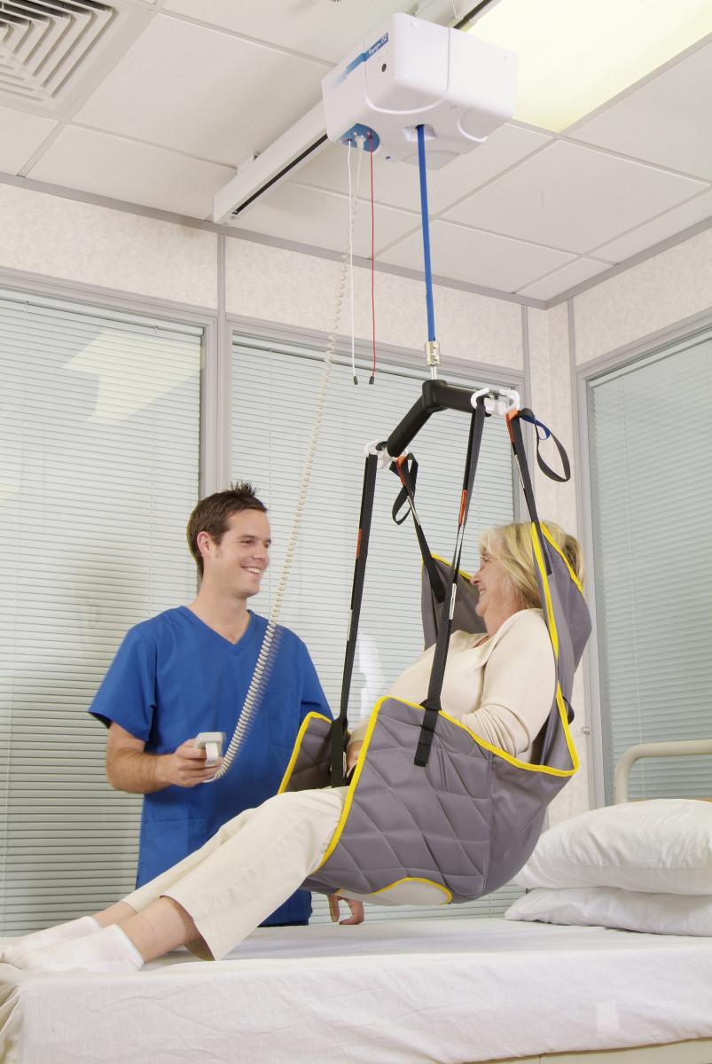 Ceiling hoist operated by one care worker to lift a women out of bed using a sling