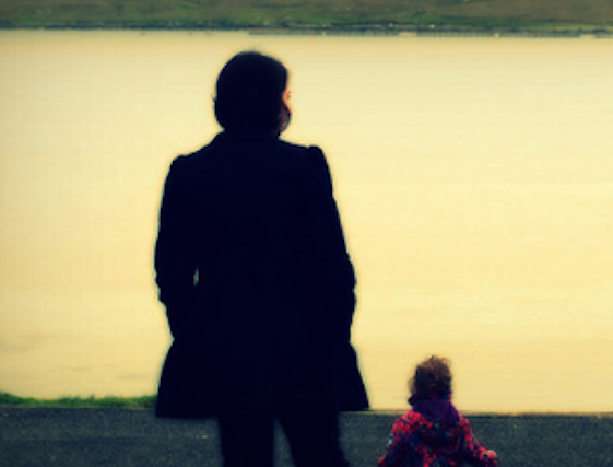 Artistic and somber picture of mother and daughter standing together, staring out to sea