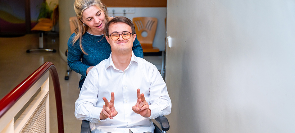 Young man sitting in a wheelchair giving a thumbs up sign