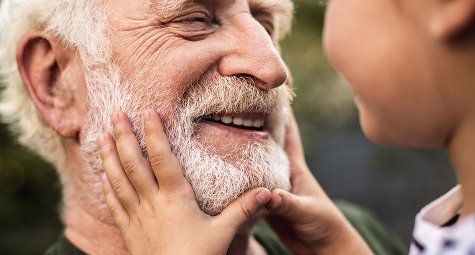 Laughing grandparent with their grandson holding their face