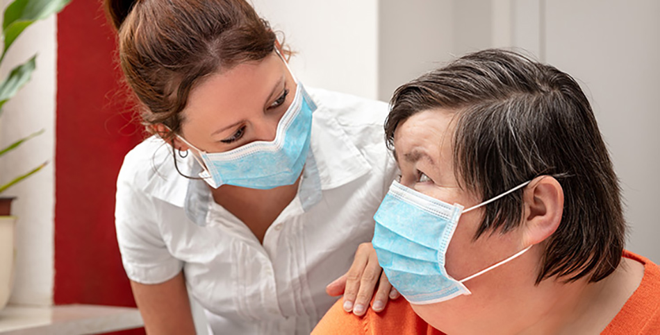 Support worker with a participant, both wearing masks