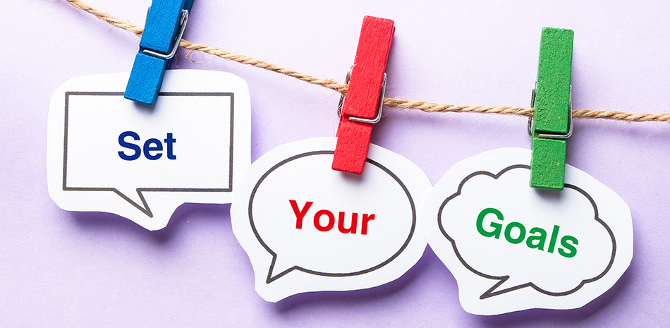 a line with 3 coloured wooden pegs hanging on it. Each peg holds a piece of card with a word on it. The words are set, your and goals