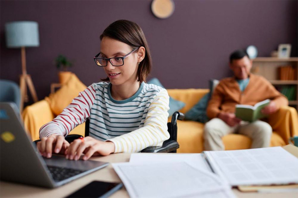 Young woman typing on laptop keyboard with father seated in background reading