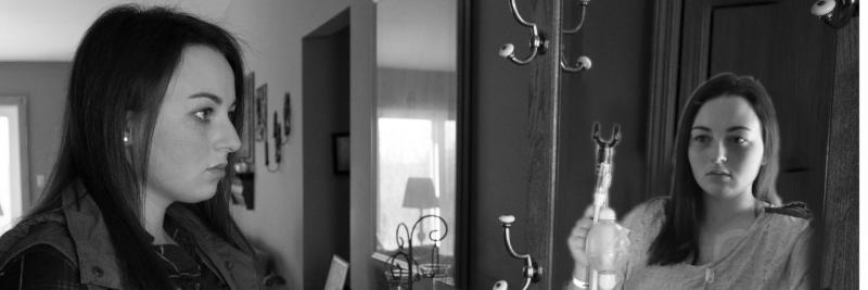 forlorn girl stares at reflection and sees herself as sick and holding medical equipment