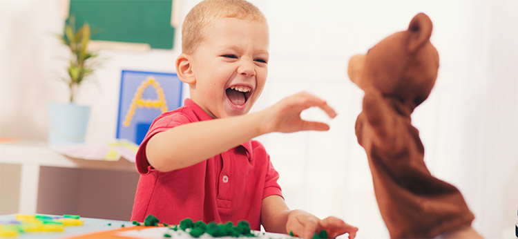 Boy playing with a bear puppet during his assessment