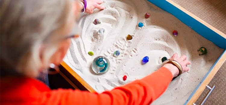 woman engaging in sand therapy