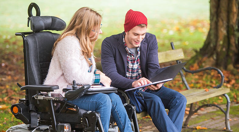 A Support Coordiantor sitting with a Participant looking at an iPad