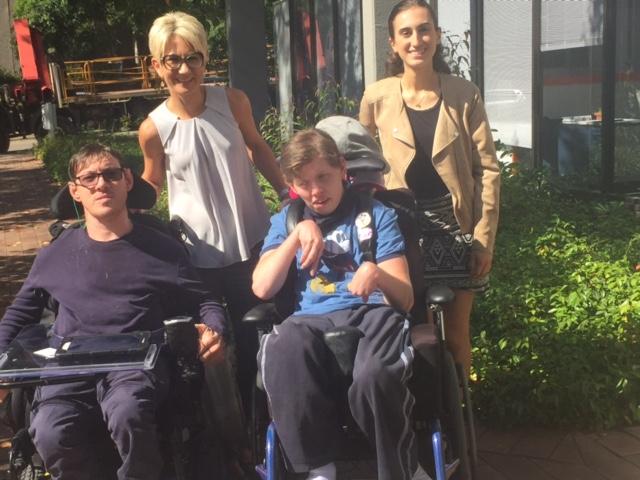 Nicole and Kate from MyCareSpace standing behind 2 people in wheelchairs