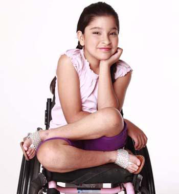 lourdes sits cross legged in her wheelchair and smiles with her face resting in one hand