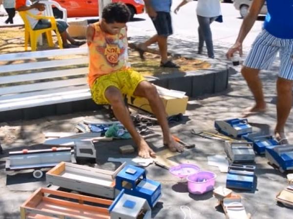 Geraldo Pereira sitting outside in public on a bench, where he builds his toys 