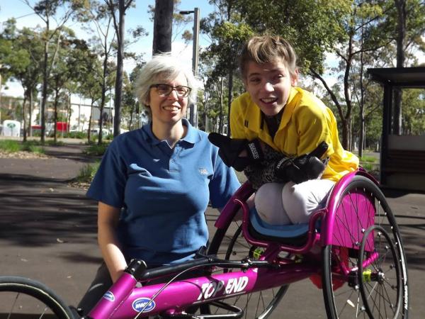 sarah in her multisport wheel chair with her trainer